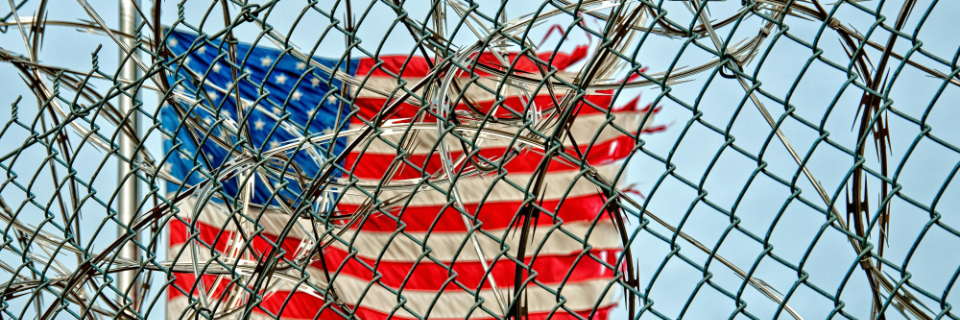 An American flag partially unfurled, edges fraying, against a global map